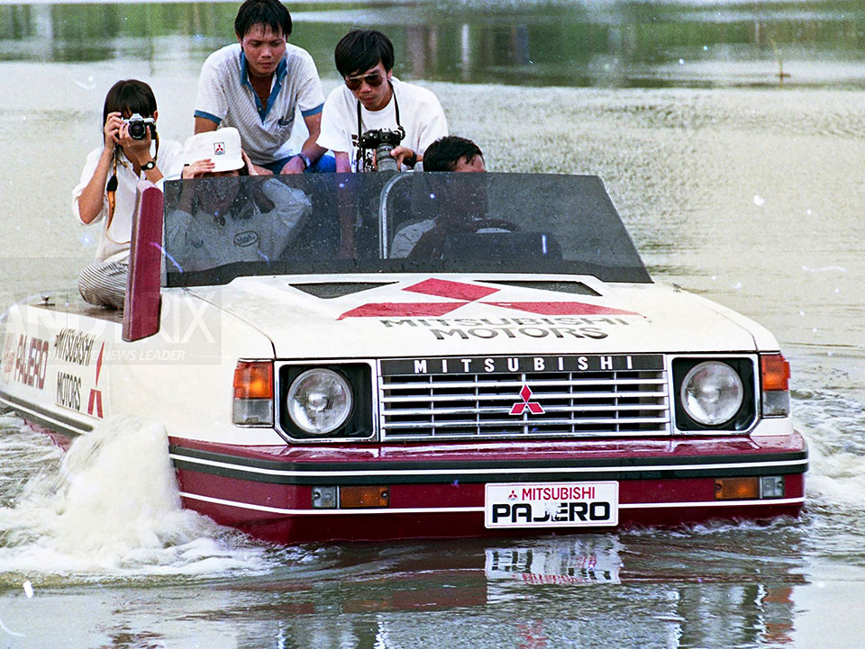 Gambar sejarah memaparkan Mitsubishi Pajero El Lago dipandu turun dari tanjakan kayu khas dan 'terjun' masuk ke dalam tasik sambil disaksikan oleh orang ramai di Bangkok International Motor Show 1988.